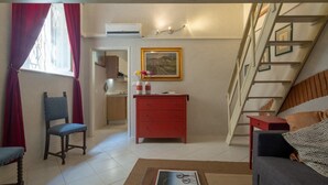 A living room with a sofa, a red dresser, a chair, a staircase, and a painting on the wall. - An apartment in the heart of Santo Spirito by Mmega (Firenze)