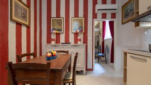 A dining area with a striped wall, a wooden table, chairs, and a buffet with fruit. - An apartment in the heart of Santo Spirito by Mmega (Firenze)