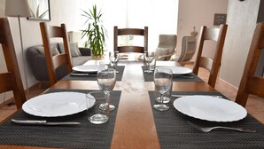 Una mesa de comedor dispuesta con platos, vasos y cubiertos, rodeada de sillas de madera.