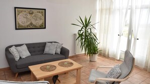 Una sala de estar con un sofá gris, una mesa de centro de madera, una planta en maceta y un sillón.