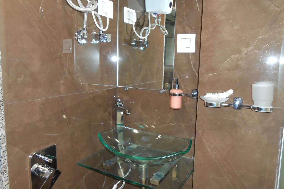 A bathroom with a glass sink, a mirror, and a towel rack.