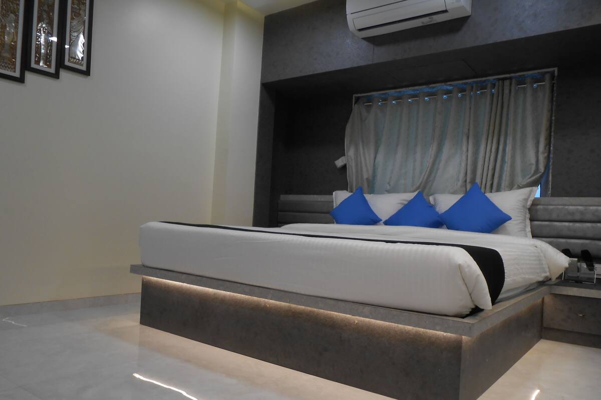 A modern bedroom with a large bed, a bedside table, and a wall-mounted air conditioner.