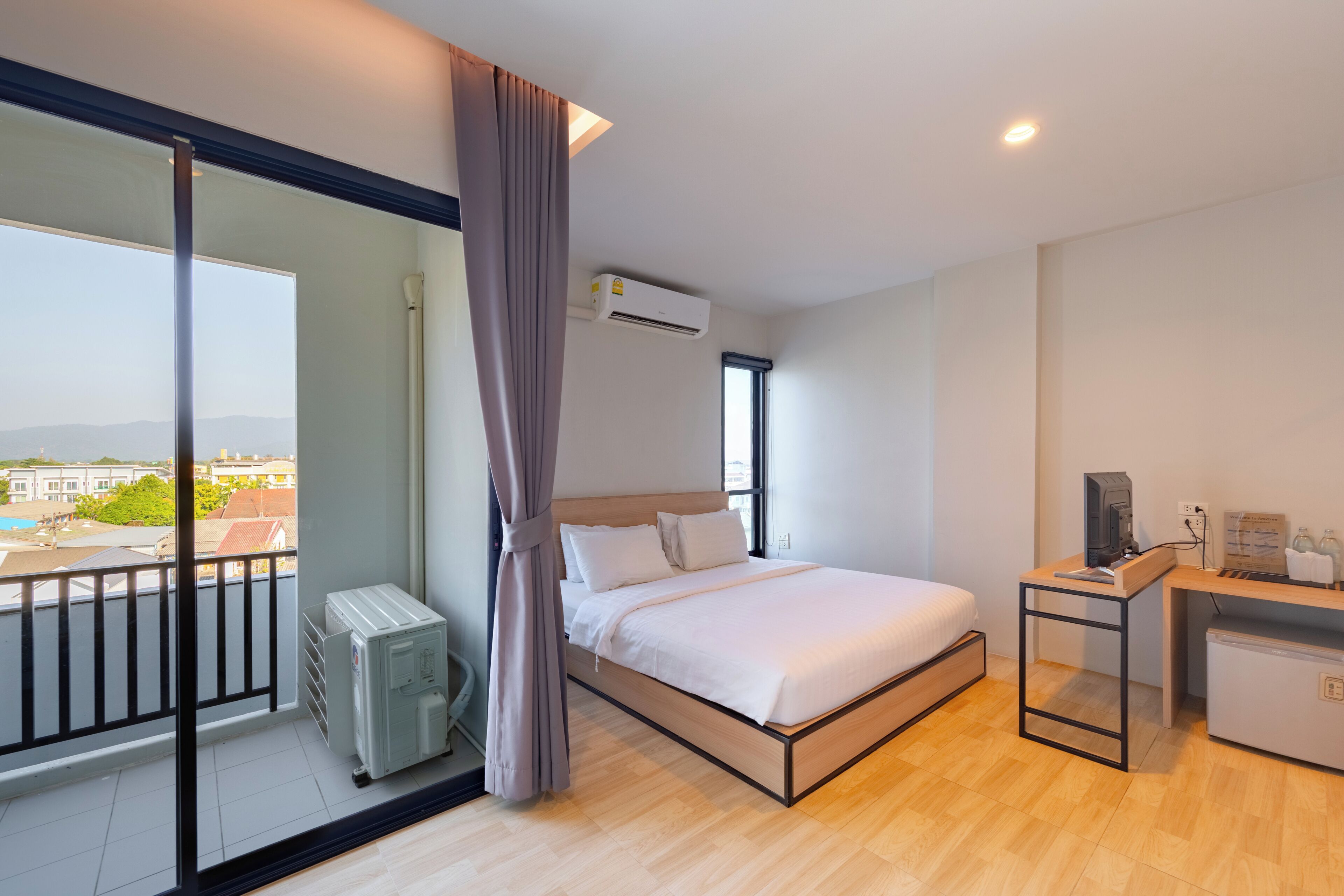 Una habitación de hotel moderna con balcón, una cama, un escritorio y un equipo de aire acondicionado.