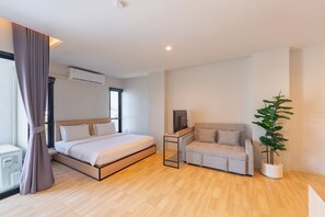 A modern bedroom with a bed, a sofa, a potted plant, and an air conditioning unit.