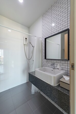 A modern bathroom with a white sink, a large mirror, and a shower with a glass door.