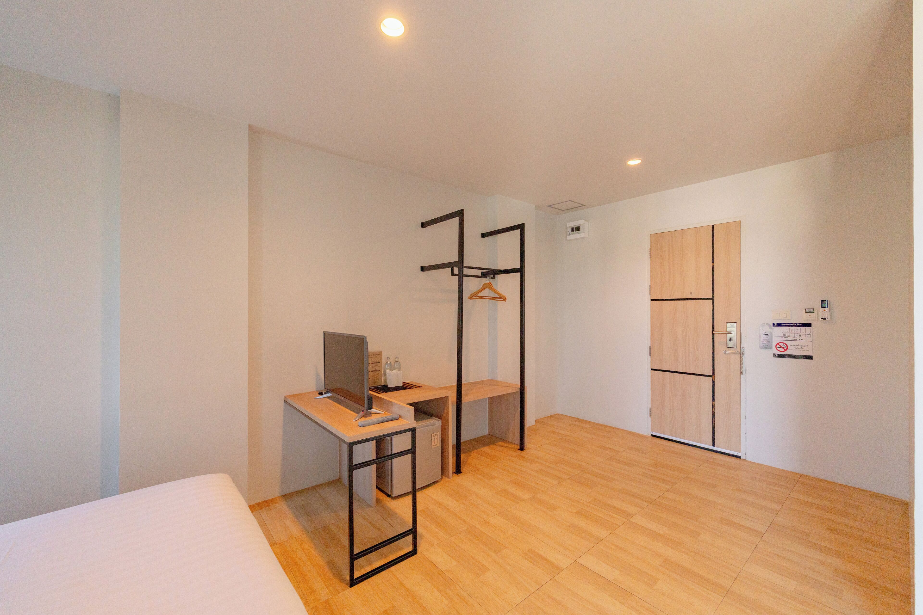 A modern hotel room with a bed, desk, and wardrobe.