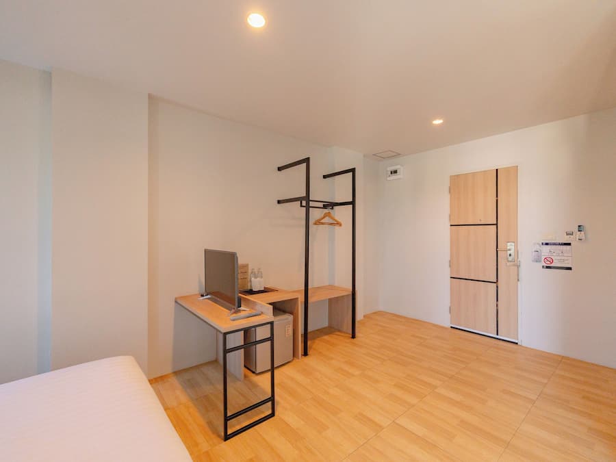 Ein modernes Hotelzimmer mit Bett, Schreibtisch und Kleiderschrank.