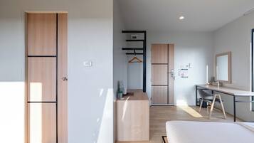 A modern hotel room with a bed, desk, and wardrobe.