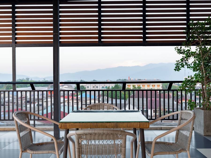 A balcony with a table and chairs, a view of a cityscape, and a potted plant.