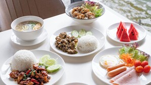Una mesa con diferentes platos, un bol de sopa y vista a una fuente de agua.