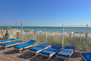 A beachside lounge area with sunbeds and a view of the ocean.