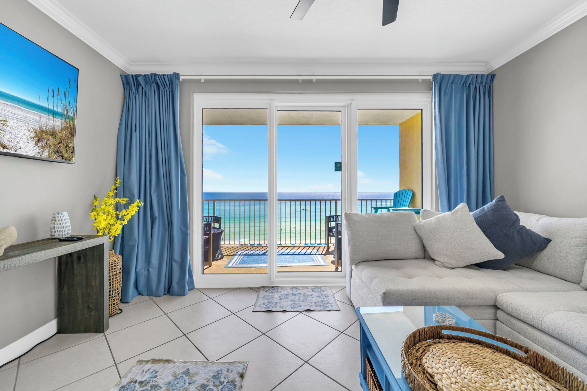 A modern living room with a sofa, a coffee table, and a view of the ocean through a sliding glass door.