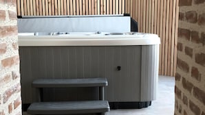 A spa area with a hot tub, a bench, and a tiled floor. - CHEZ LULU, town house overlooking the Beuvron (Candé-sur-Beuvron)