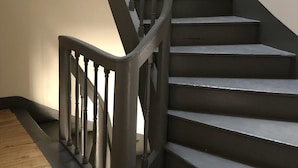 A staircase with a dark metal railing and wooden steps. - CHEZ LULU, town house overlooking the Beuvron (Candé-sur-Beuvron)
