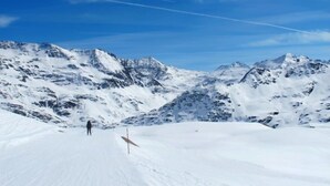 A snow-covered mountain landscape with a clear sky and a single person walking on a trail. - San Anton by Interhome (Bormio)