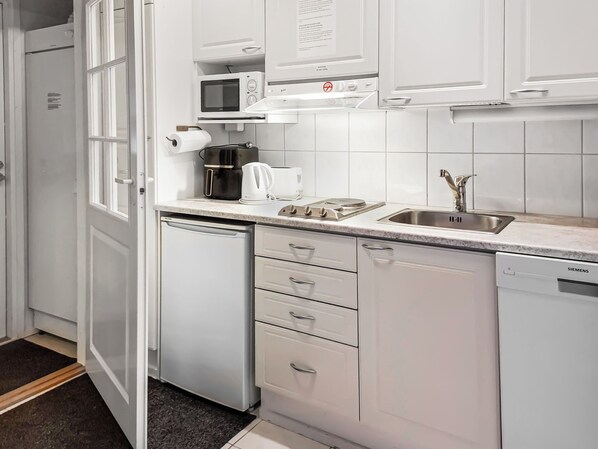 A modern kitchen with white cabinetry, a built-in microwave, a coffee maker, and a dishwasher.