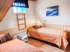 A bedroom with two beds, a ladder, a nightstand, a lamp, and a painting on the wall.