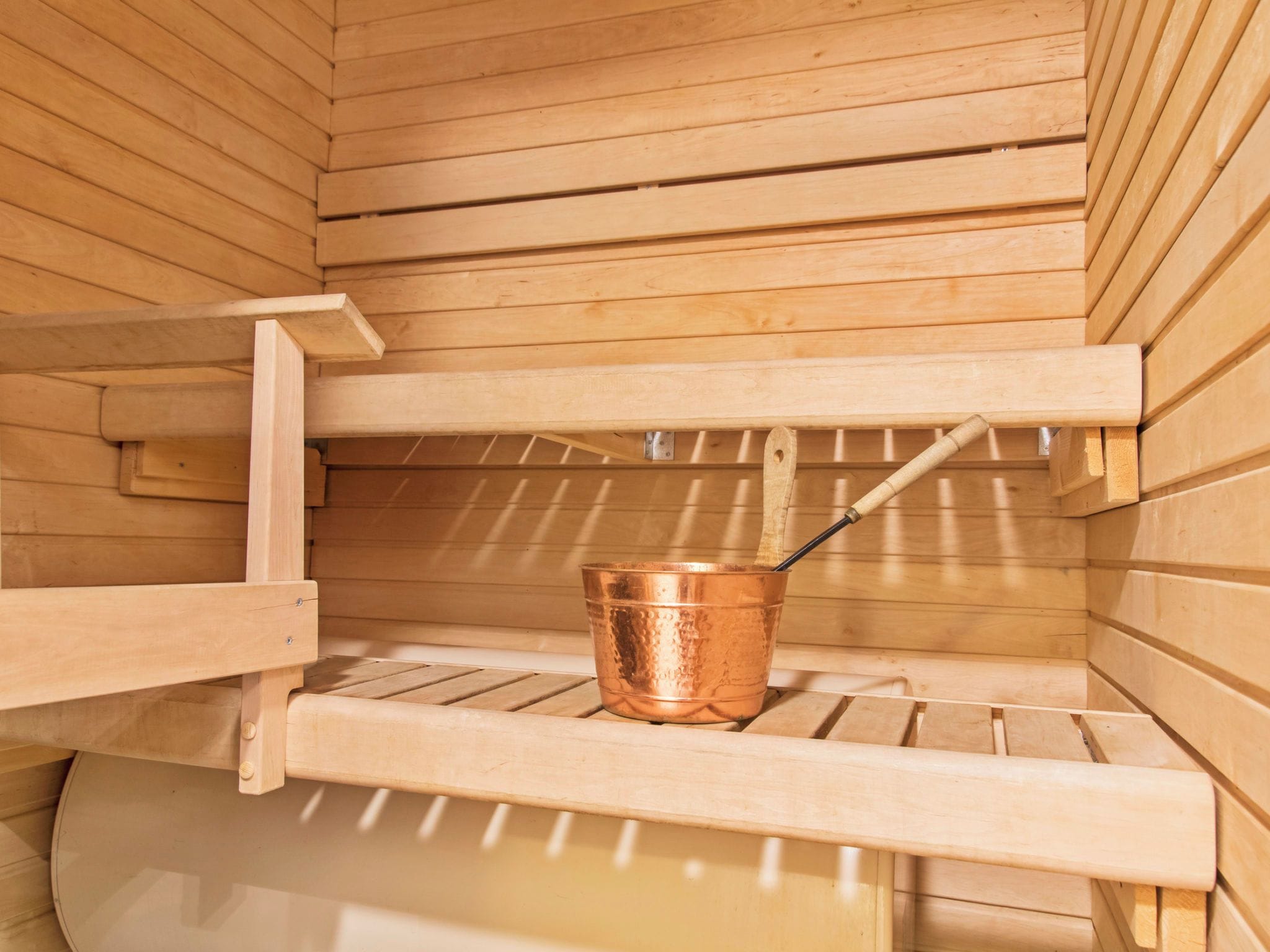 Eine Holzsauna mit einem Kupferbecken und einer hölzernen Sitzbank.
