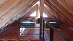 Een zolderkamer met twee bedden, houten balken en een dakraam.