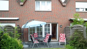 A brick house with a patio, a table with chairs, and a covered area. - Vacation home Nemo, holiday apartment rental North Sea - Holiday home Nemo (Varel)