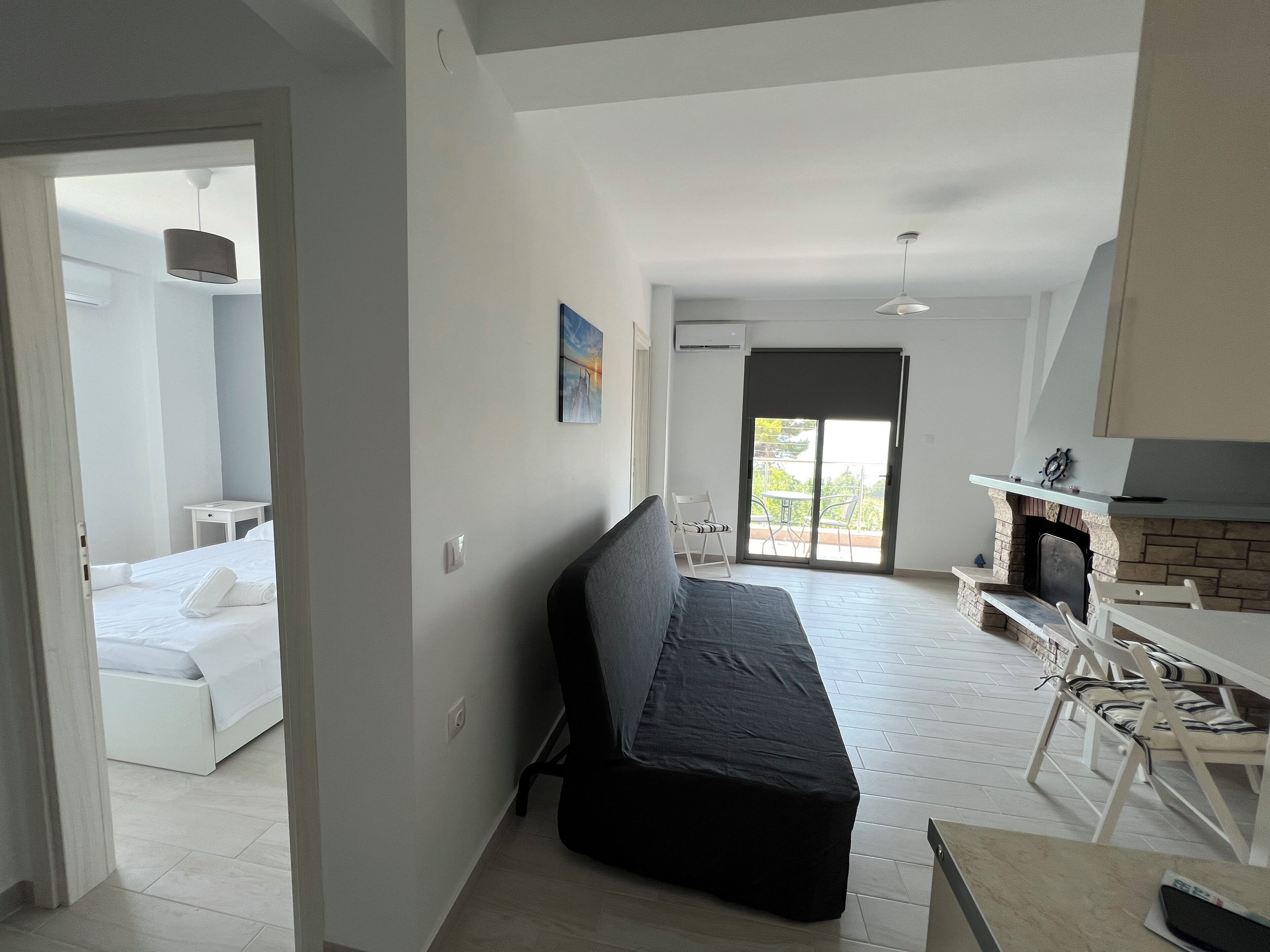 A modern room with a bed, a sofa, a dining area with chairs, and a fireplace.