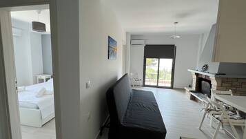 A modern room with a bed, a sofa, a dining area with chairs, and a fireplace.