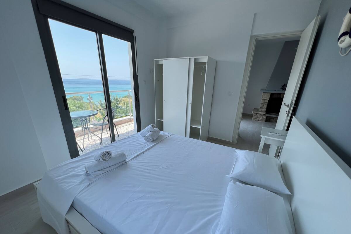A hotel room with a bed, a wardrobe, and a view of the sea.