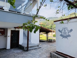 Un edificio con un patio empedrado de piedra, una puerta de madera y una pérgola cubierta de parras.