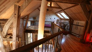 Une chambre mansardée au style rustique, avec des poutres apparentes, un plafond en pente et un pilier central.