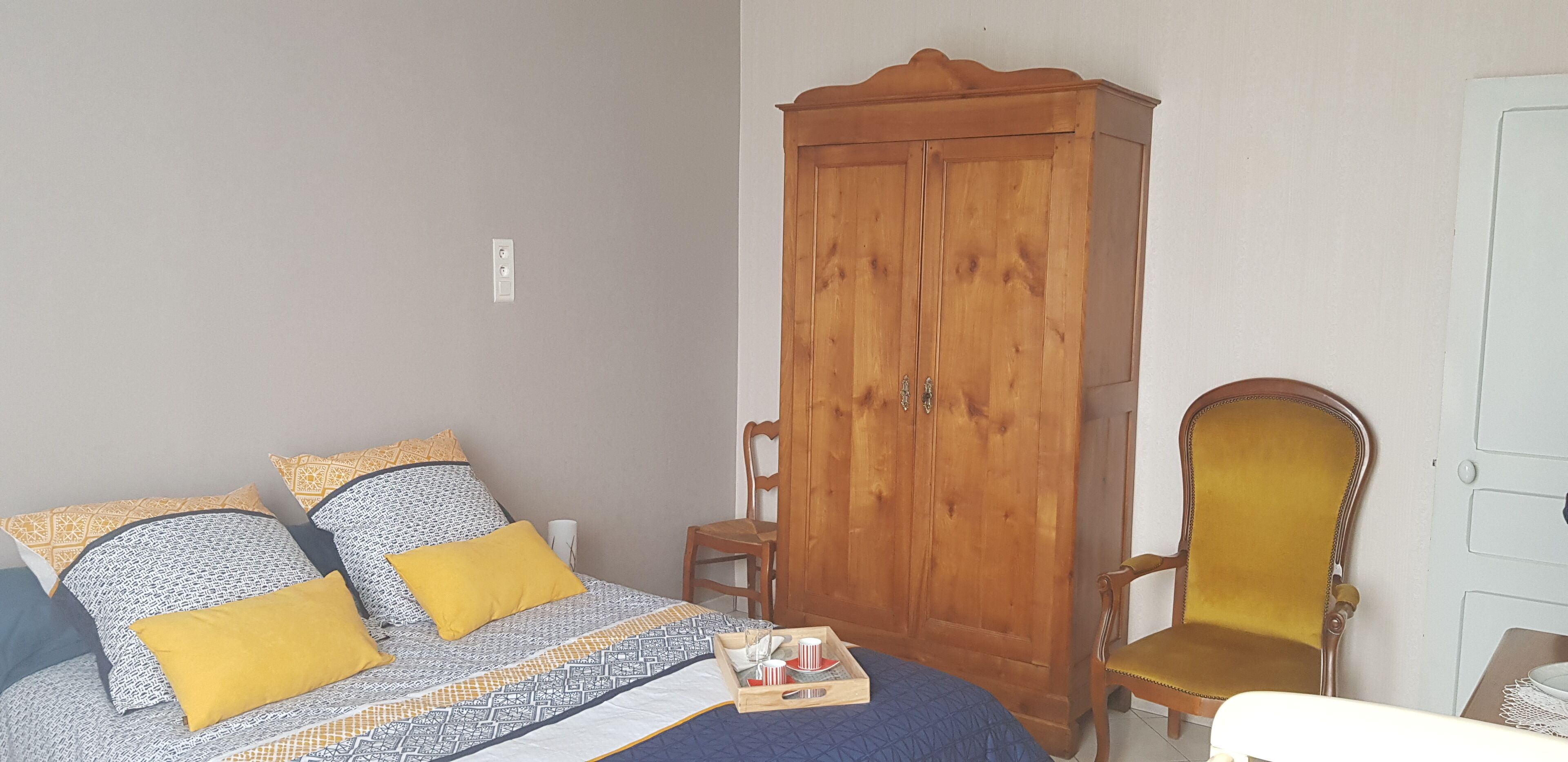 Un dormitorio con cama, un armario de madera y un sillón amarillo.