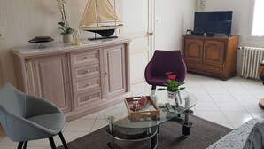 A living room with a glass coffee table, a purple chair, a wooden cabinet, a television, and a potted plant. - Cottage for 7 people 15 minutes from Puy du Fou (Pouzauges)