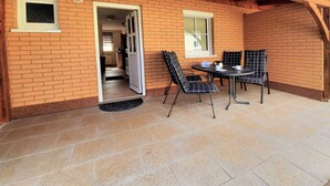 Un patio con mesa y sillas, una puerta que da a un espacio interior y una ventana.
