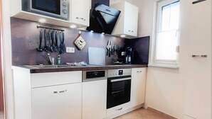 Una cocina moderna con armarios blancos, microondas, estufa y cafetera.