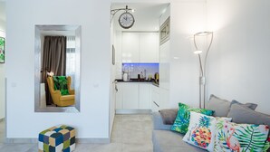 Un soggiorno moderno con un divano, cuscini colorati, un tavolino e vista sulla cucina.
