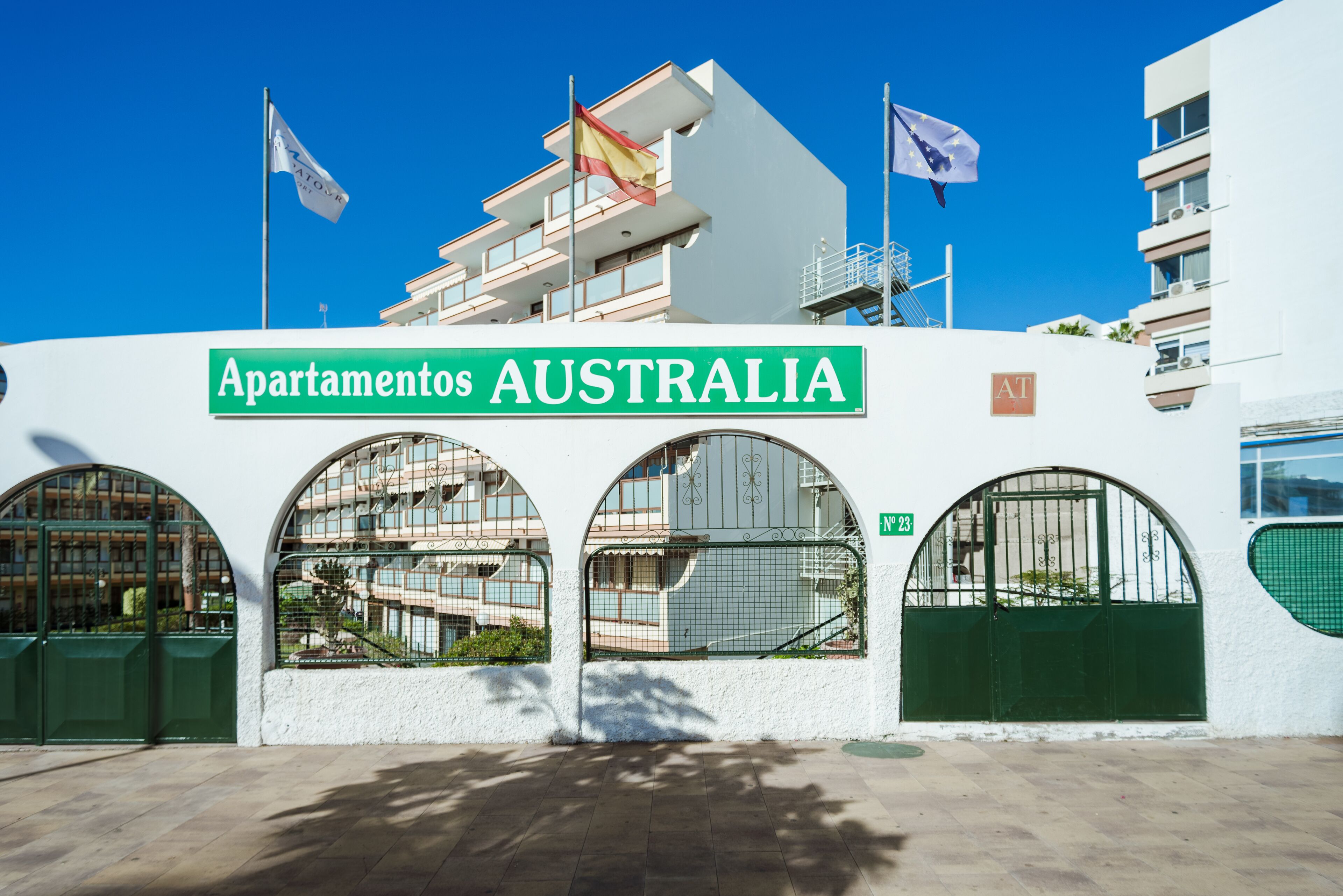 A building with a sign reading "Apartamentos AUSTRALIA" and three arched windows.