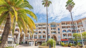 A hotel with multiple balconies, palm trees, and outdoor seating areas. - Royal Marine by Interhome (Fréjus)