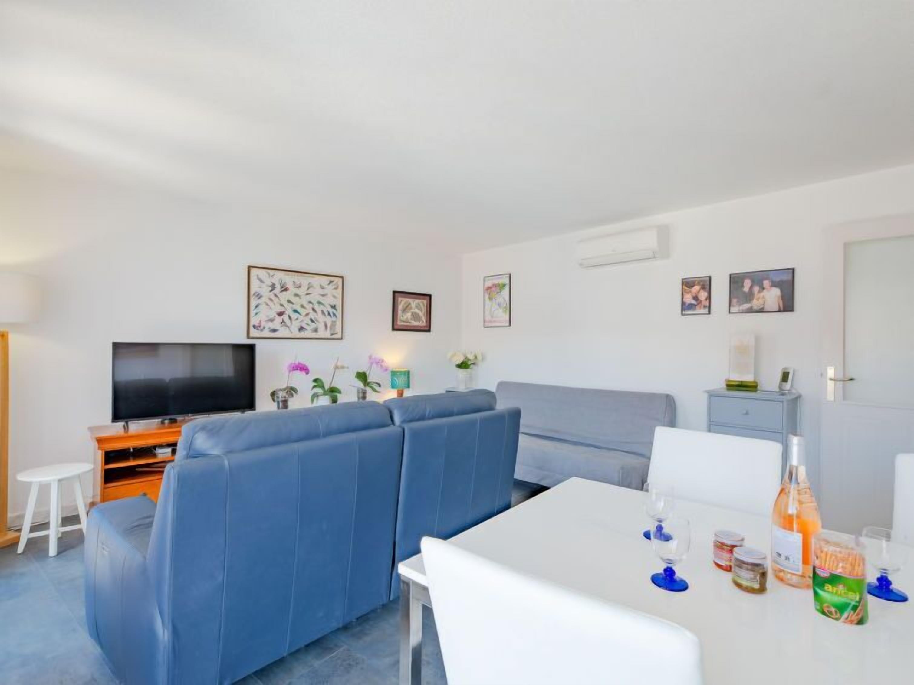 Un salon moderne avec un canapé, un téléviseur et une table à manger où sont disposés des plats et des boissons.
