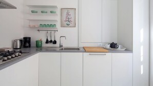 Een moderne keuken met witte kastjes, een gasfornuis, een koffiezetapparaat en een spoelbak.