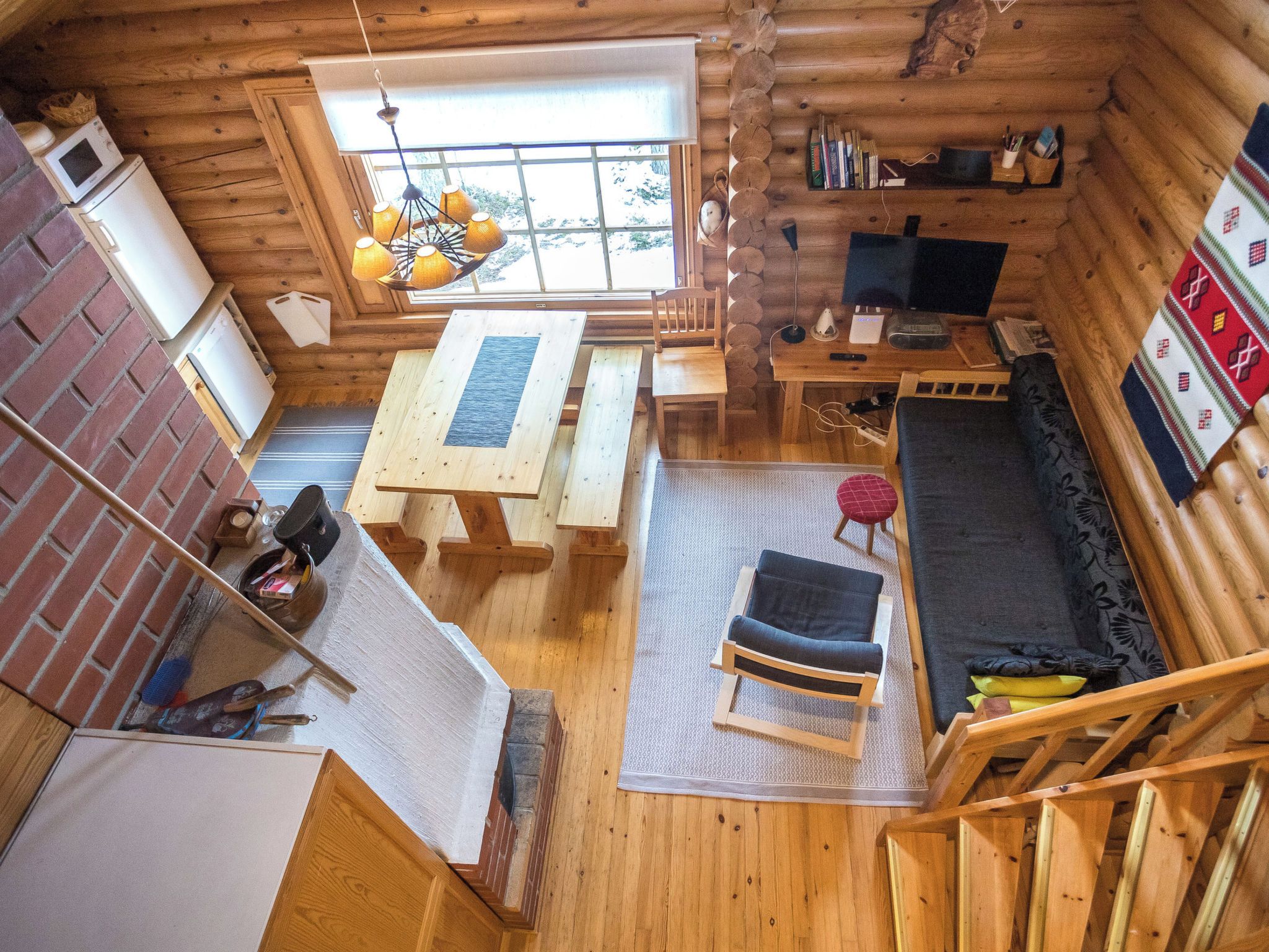 L’intérieur d’une cabane en rondins comprend un coin repas, un canapé, un téléviseur et une cheminée.