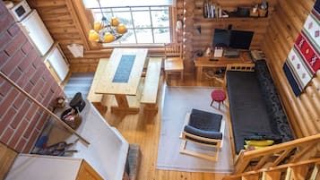 L’intérieur d’une cabane en rondins comprend un coin repas, un canapé, un téléviseur et une cheminée.