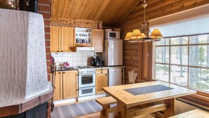 A cozy cabin-style kitchen with wooden cabinets, a stove, a refrigerator, and a large window offering a view of the forest. - Jänkäluppo 1 by Interhome (Äkäslompolo)