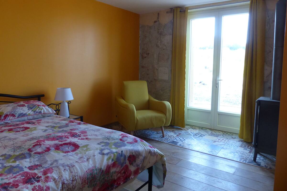 Ein Hotelzimmer mit Bett, Stuhl, Lampe und Blick durch eine Tür.