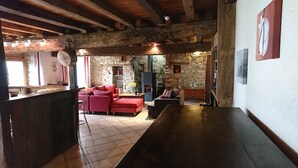 Un intérieur rustique avec des poutres apparentes, une cheminée en pierre et un canapé rouge.