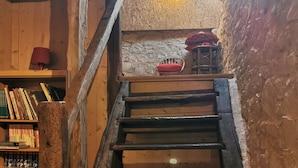 Un escalier en bois dans un intérieur rustique, avec une bibliothèque et une lampe.