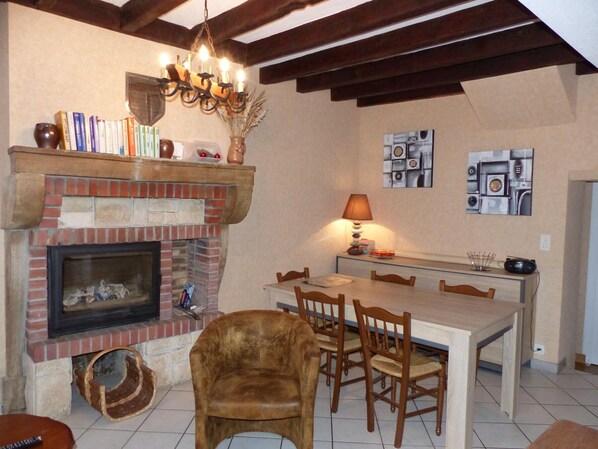 Un coin repas chaleureux avec une cheminée en briques, une table à manger en bois et des chaises.
