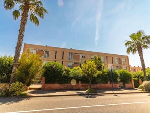 A multi-story building with a flat roof, surrounded by palm trees and greenery. - Les Ilaires by Interhome (Le Lavandou)