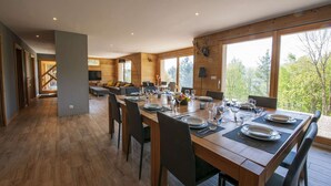 A spacious dining area with a long wooden table set for a meal, surrounded by chairs. - Inuï Grand Chalet - 5-star luxury spa (Muhlbach-sur-Munster)