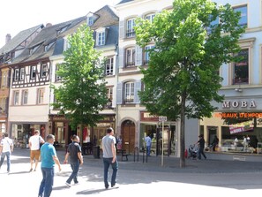A street with buildings, trees, and people walking.