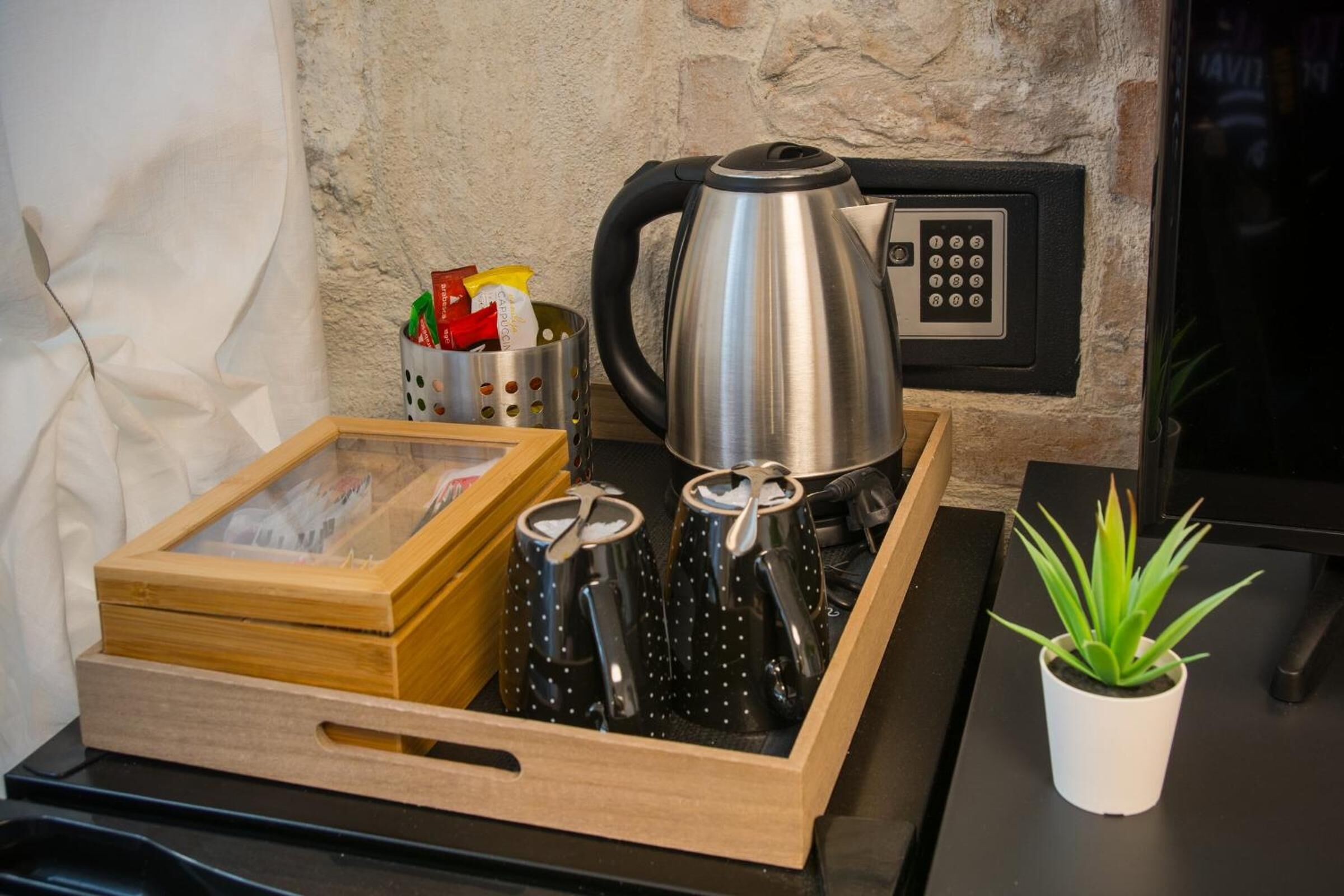 Una bandeja con una tetera, tazas, una caja de madera y una planta en maceta.