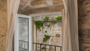 A room with a stone wall, a window with a white frame, and a balcony with a black railing. - 7heaven Luxury Rooms Palace (Split)